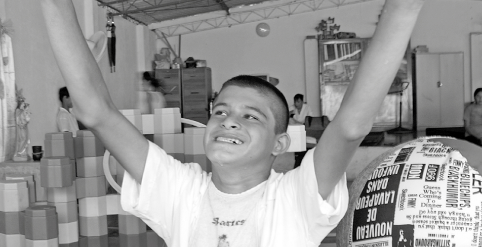 Estudiante levantando los brazos dentro de un espacio escolar, rodeado de materiales utilizados en actividades pedagógicas.