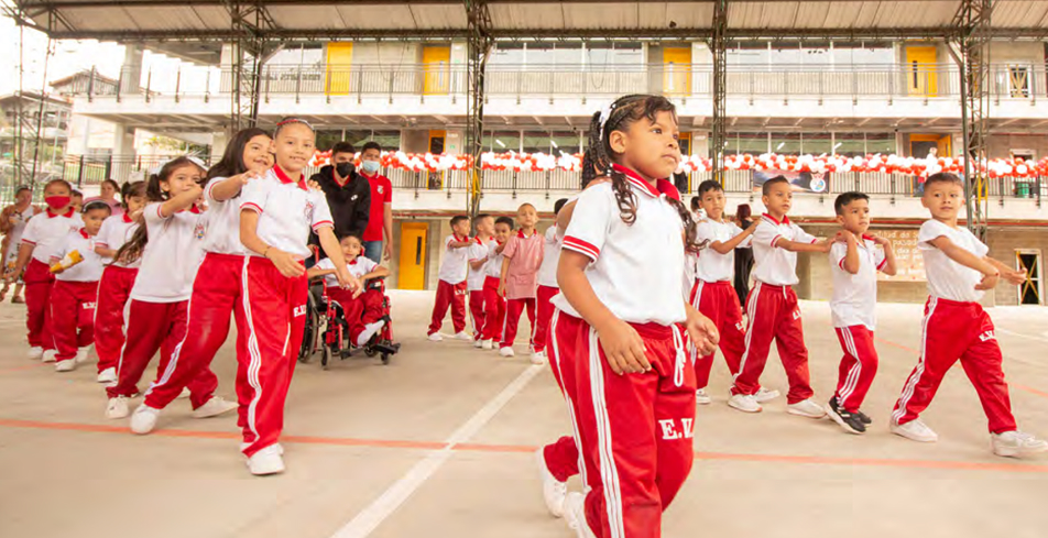 Grupo de niños en uniforme escolar realizando una actividad grupal en una cancha cubierta de su institución.